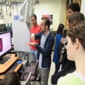 Staff member Eric Roth (center) explains to visiting students how one of NUANCE's instruments works.